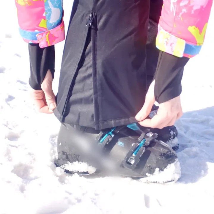 Snow bib leg with zippered ankle pulled down over a ski boot to keep snow out